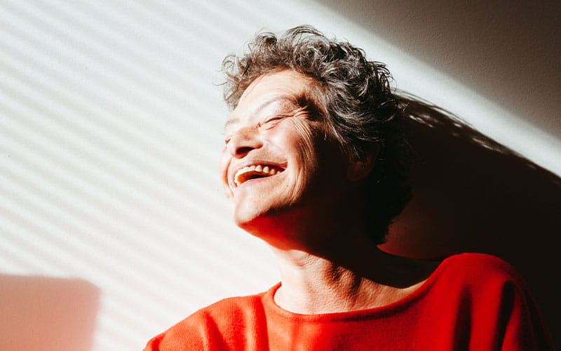 Une femme souriante portant un pull rouge 
