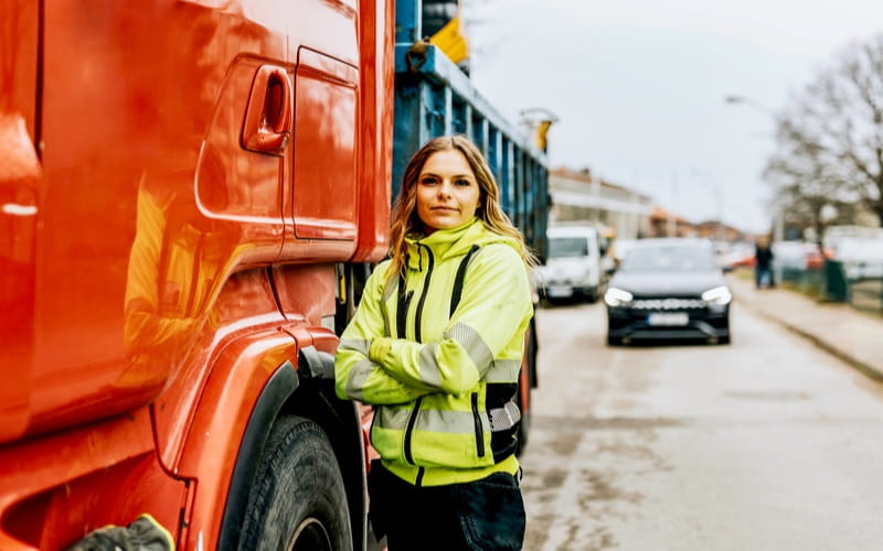  une femme évoluant dans le secteur du transport à côté d’un poids lourd
