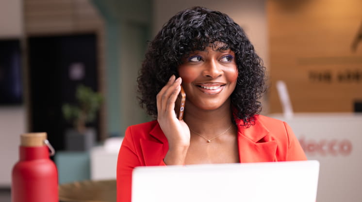 une femme souriante entrain de passer un appel téléphonique dans un environnement professionnel 