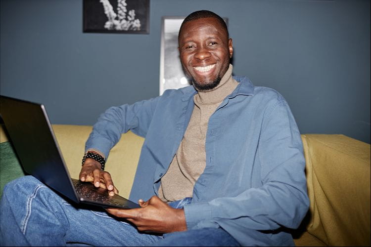 un intérimaire souriant travaillant sur son ordinateur portable 