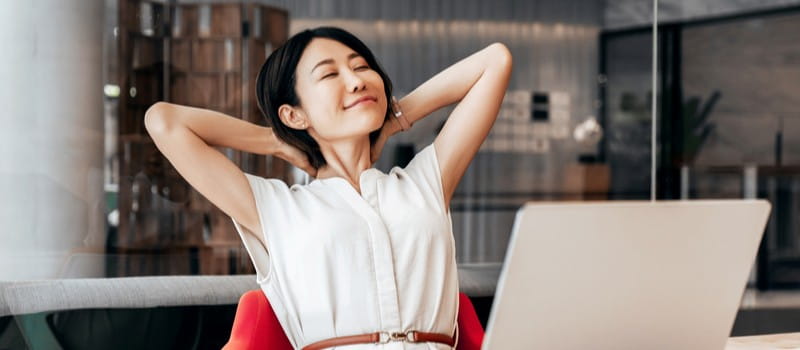 Une salariée souriante et motivée travaillant sur son ordinateur portable lors de la période estivale Une salariée souriante et motivée travaillant sur son ordinateur portable lors de la période estivale