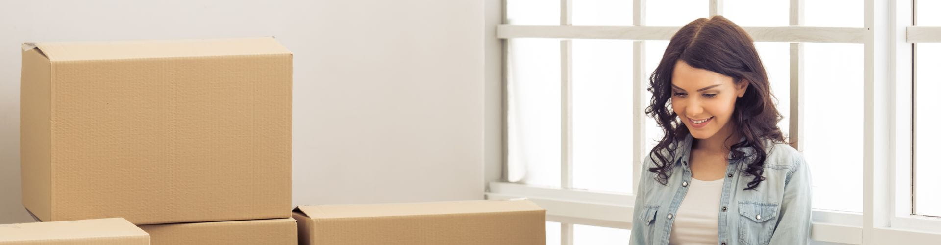 une femme souriante à côté de cartons de déménagement