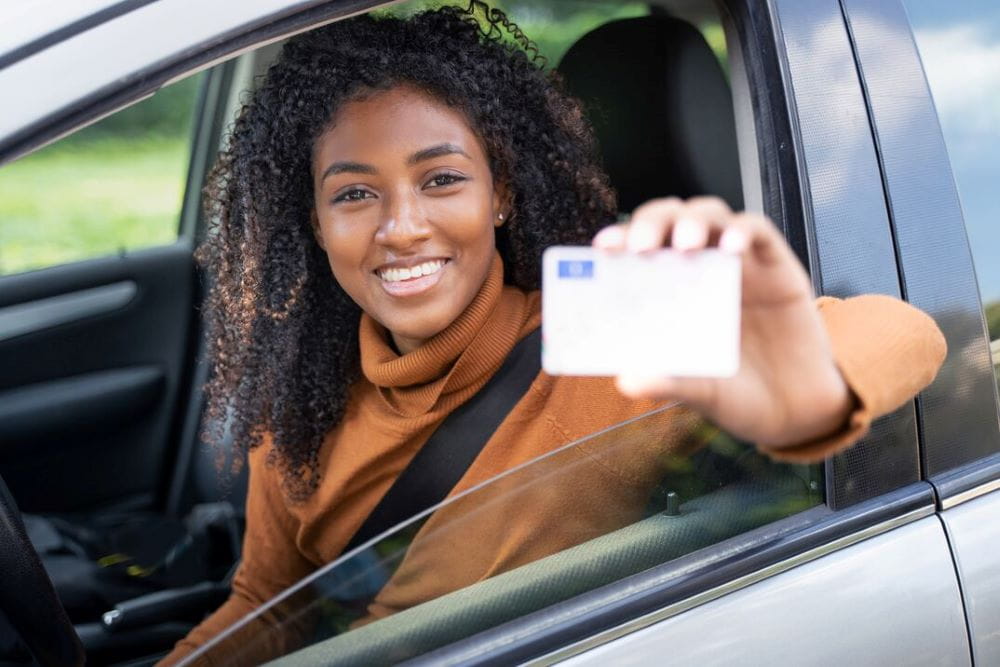 Femme heureuse au volant de sa voiture avec son permis de conduire Femme heureuse au volant de sa voiture avec son permis de conduire