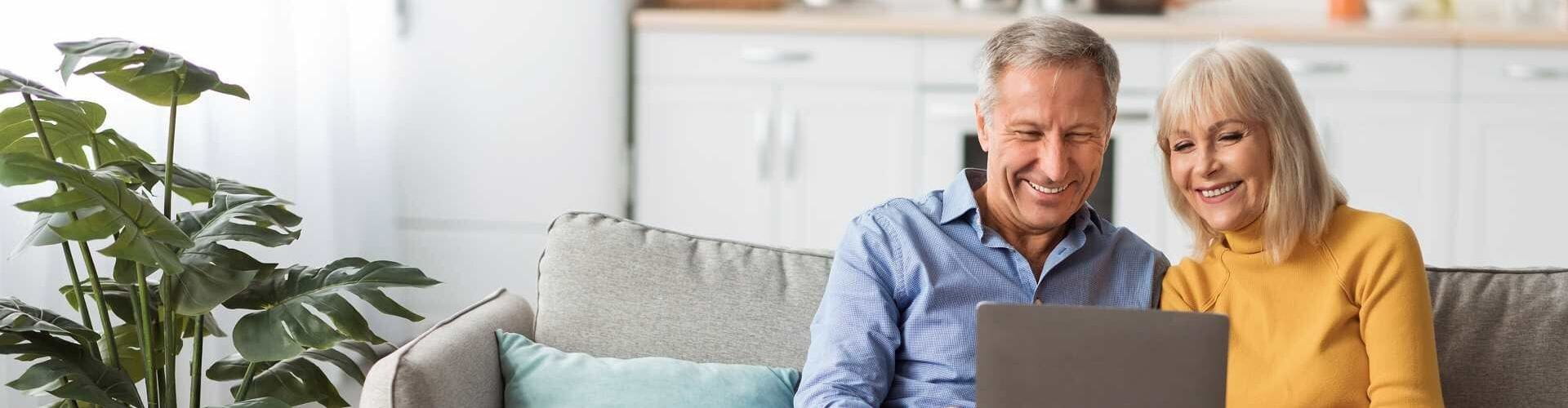  un homme et une femme, assi sur un canapé devant un ordinateur