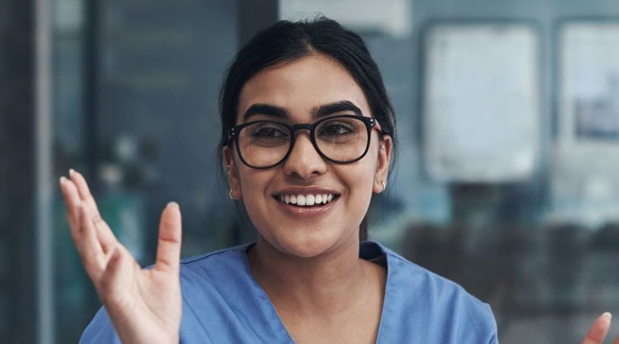 Une professionnelle de la santé souriante et portant des lunettes, parle avec deux collègues