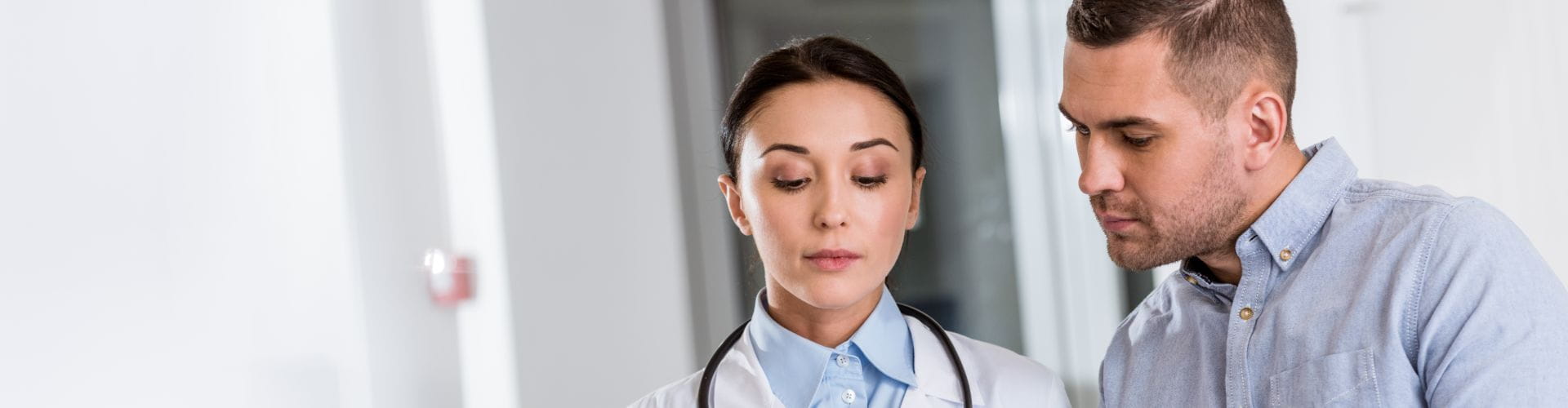Une femme médecin et un homme en chemise regardent un document