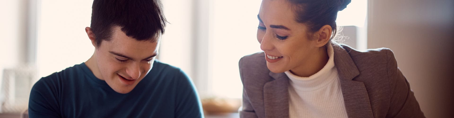 Une femme souriante aide un jeune homme à dessiner