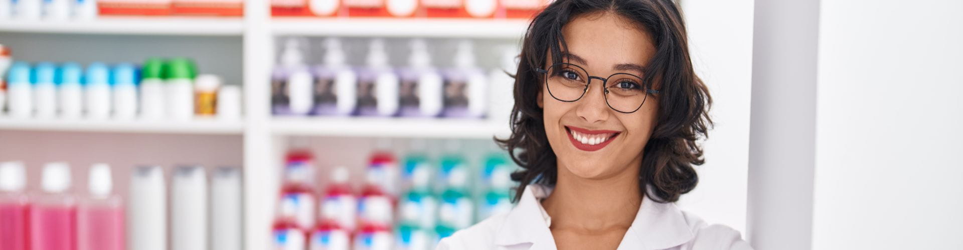 Une jeune femme pharmacienne souriante portant des lunettes dans une pharmacie