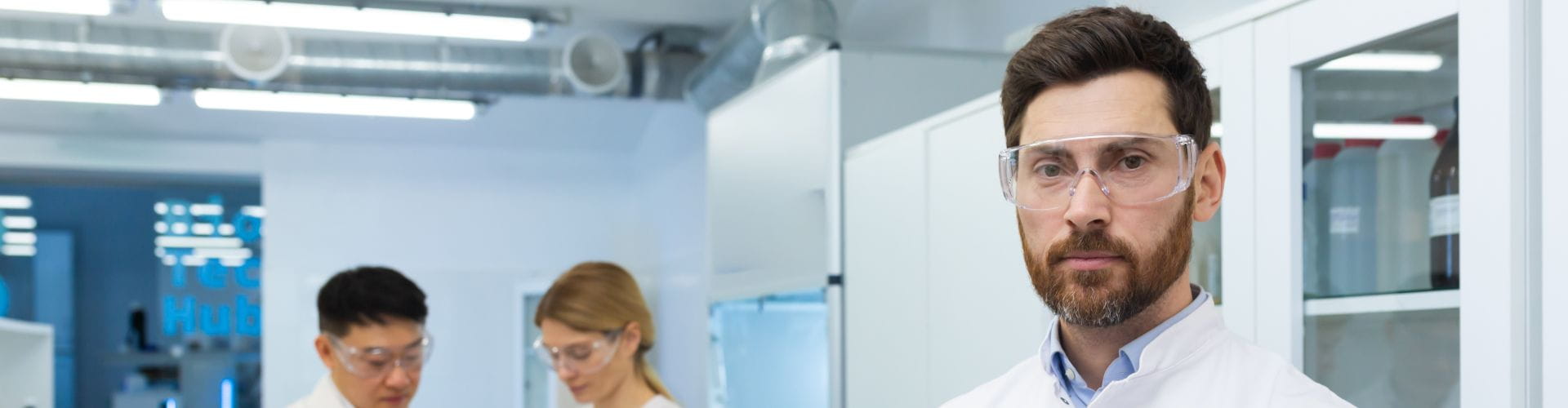 Un technicien de laboratoire portant des lunettes de sécurité et une blouse dans un laboratoire