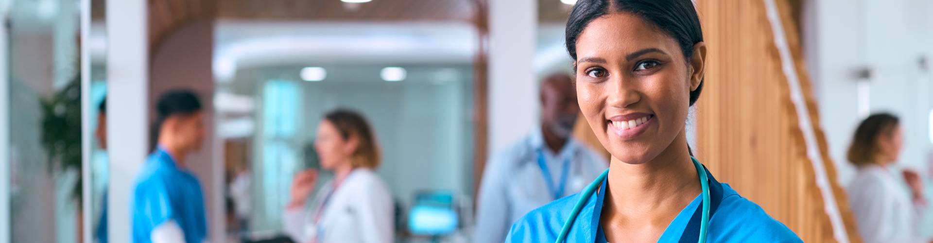Une infirmière souriante avec un stéthoscope autour du cou, regarde la caméra