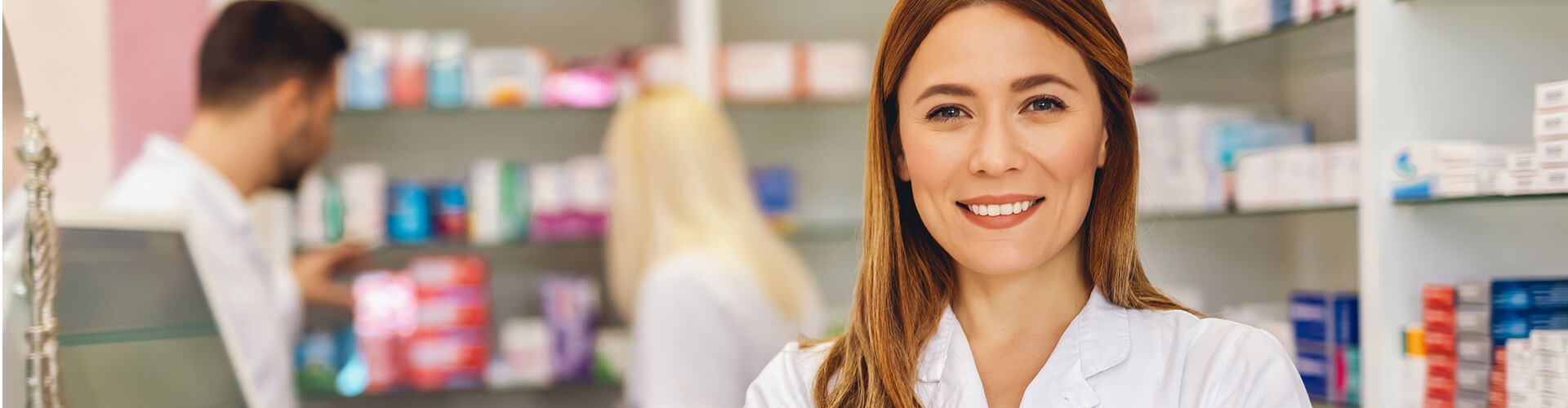 femme pharmacienne souriante devant un étal de médicament