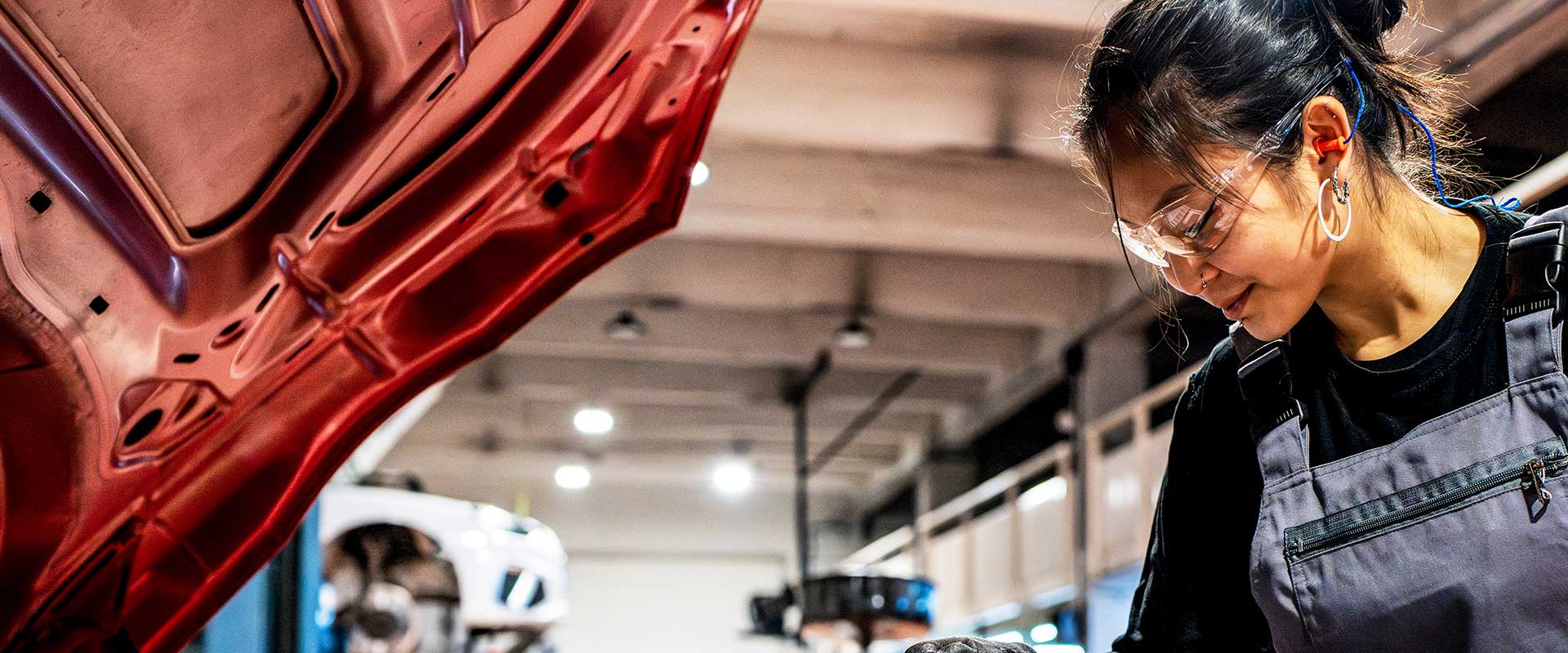 Mechanic working under car hood in automotive workshop