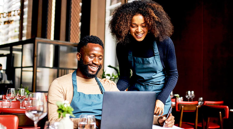 Hospitality staff reviewing work on laptop together