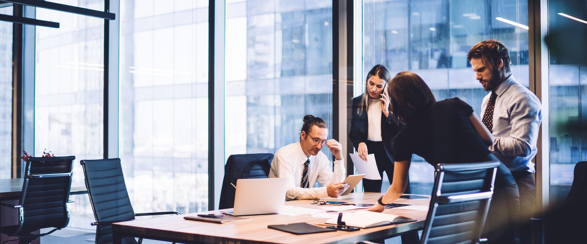 Business professionals discussing strategy in a glass-walled meeting room