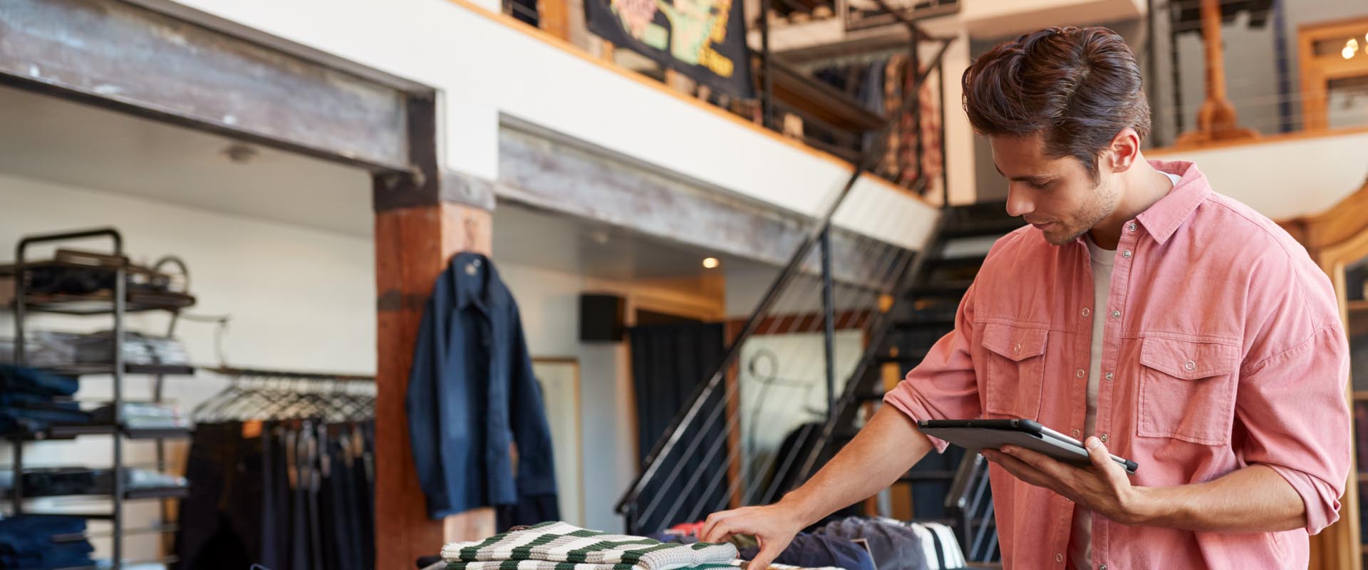 Male retail worker arranging clothes in a store