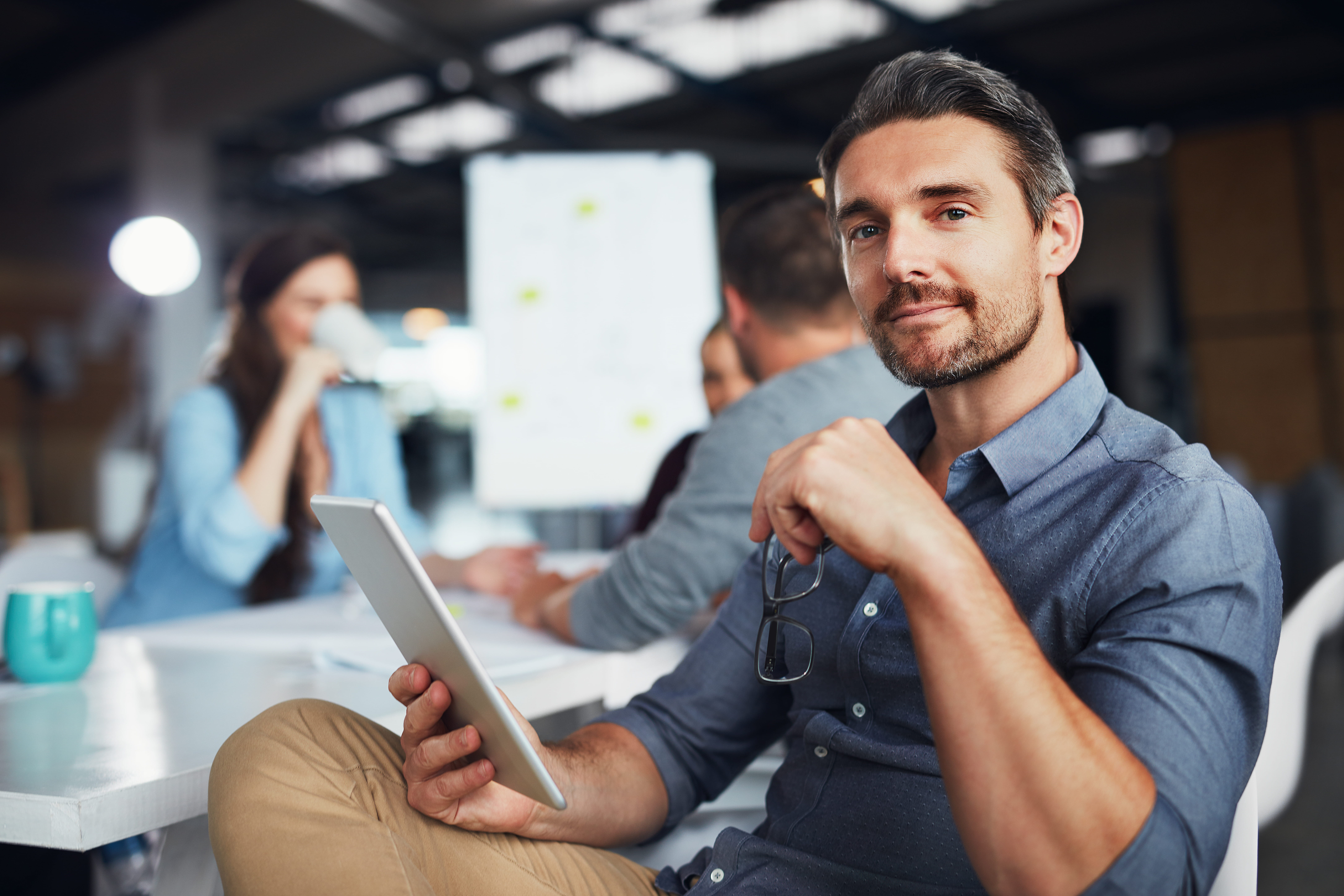 Man accepts his next Adecco job assignment on a tablet device sitting at a shared work office.