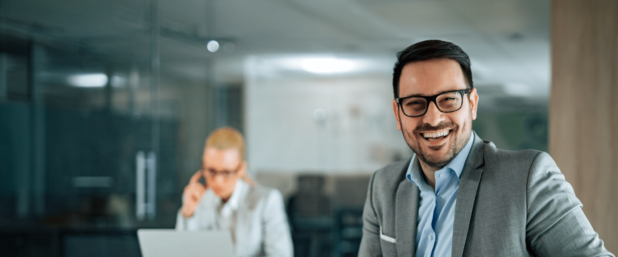 Geschäftsmann lächelt im Büro und wirkt zufrieden.