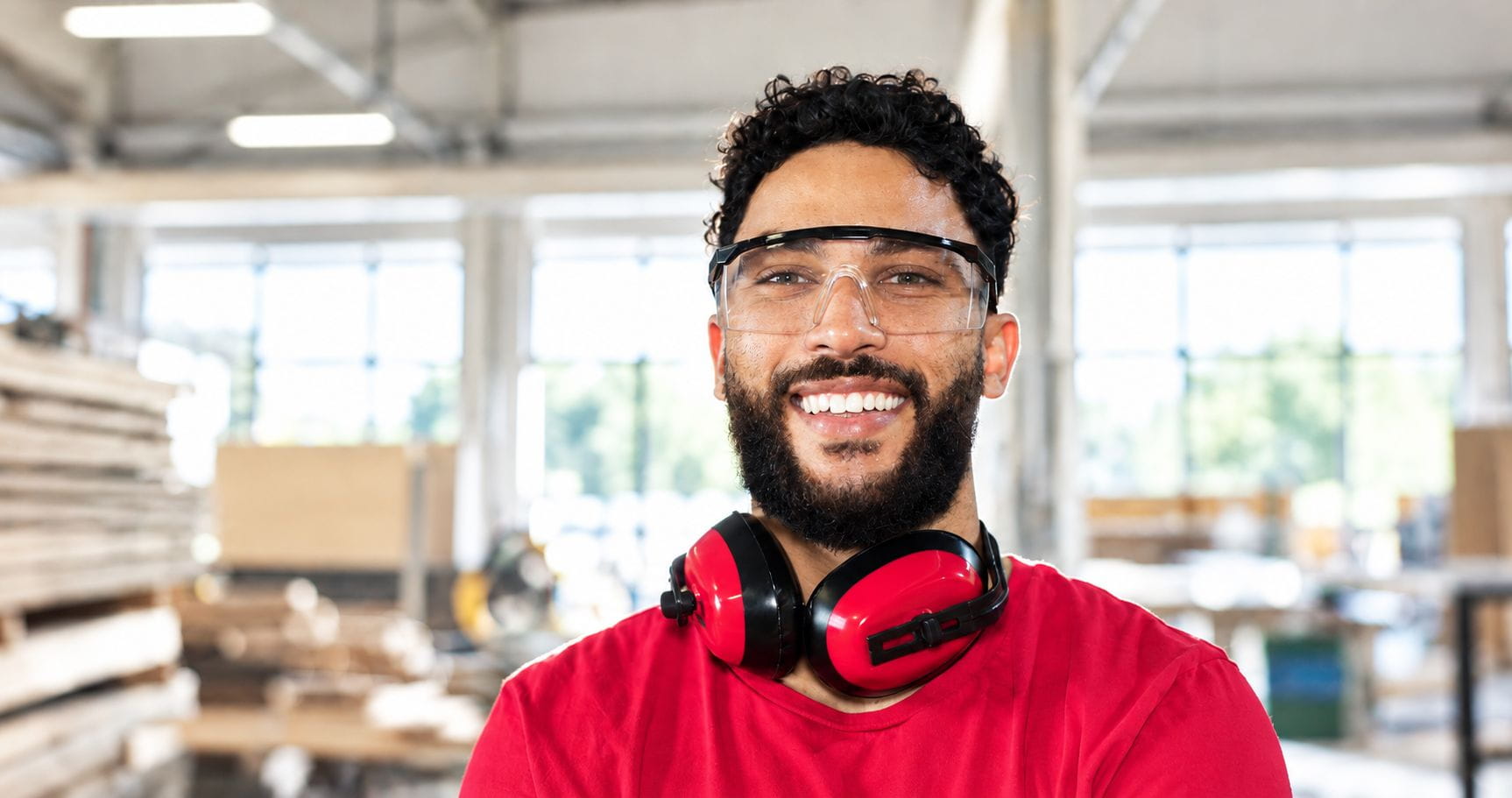 Handwerker in rotem T-Shirt lächelt in die Kamera.