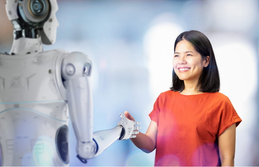 Frau und Roboter geben sich die Hand.