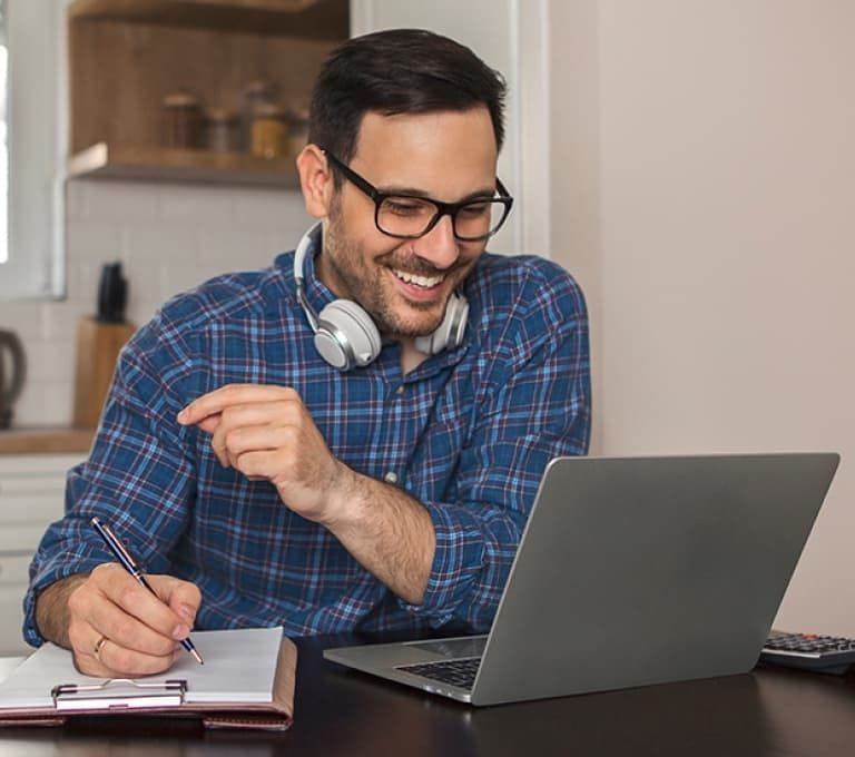 man werkt lachend achter zijn laptop