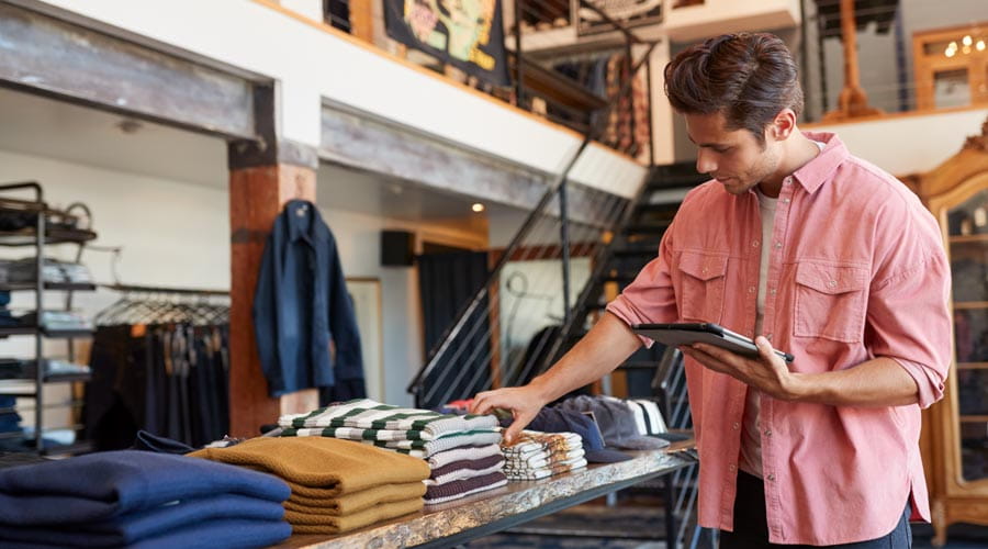 Retail worker checking stock on shelves in a clothing store