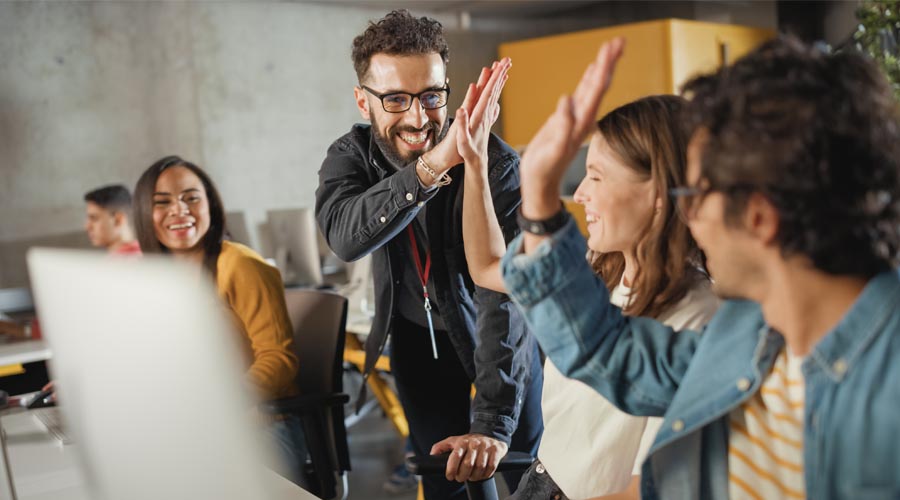 Team celebrating success with a high-five in the office