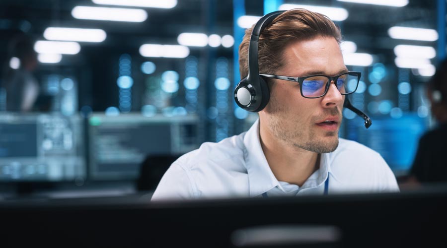 Male call centre worker  wearing a headset while  assisting a customer
