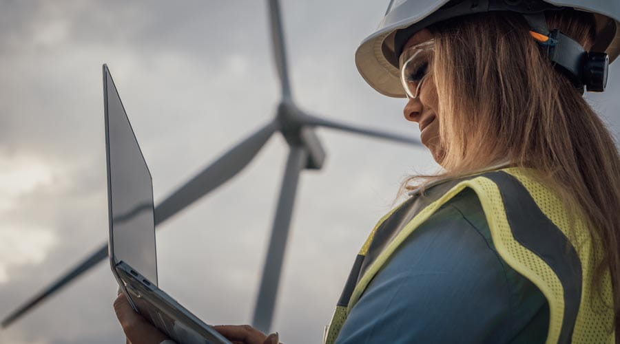 Engineer working on a  laptop at a wind farm site