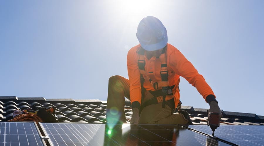 Tradesperson working on  a rooftop installing solar  panels