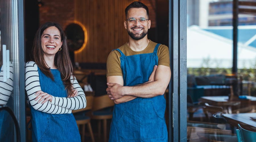 Two cafe workers  standing confidently  behind the counter