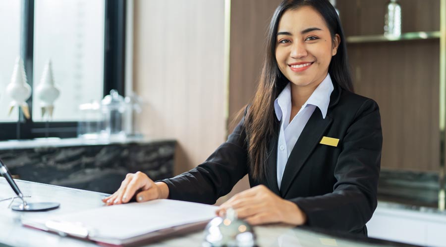 Friendly hotel receptionist  welcoming guests at the  front desk