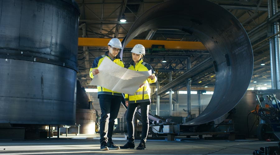 Engineers inspecting  blueprints at a large  industrial site