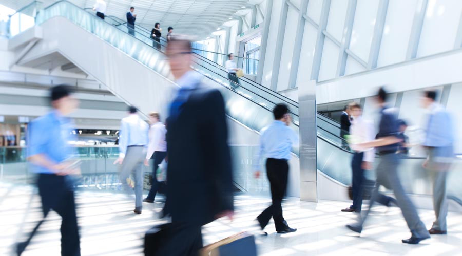 People commuting  through an office building  during rush hour