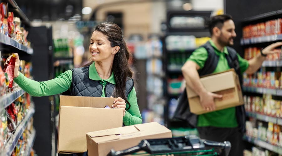 Retail workers organising  and stacking shelves in a  grocery store