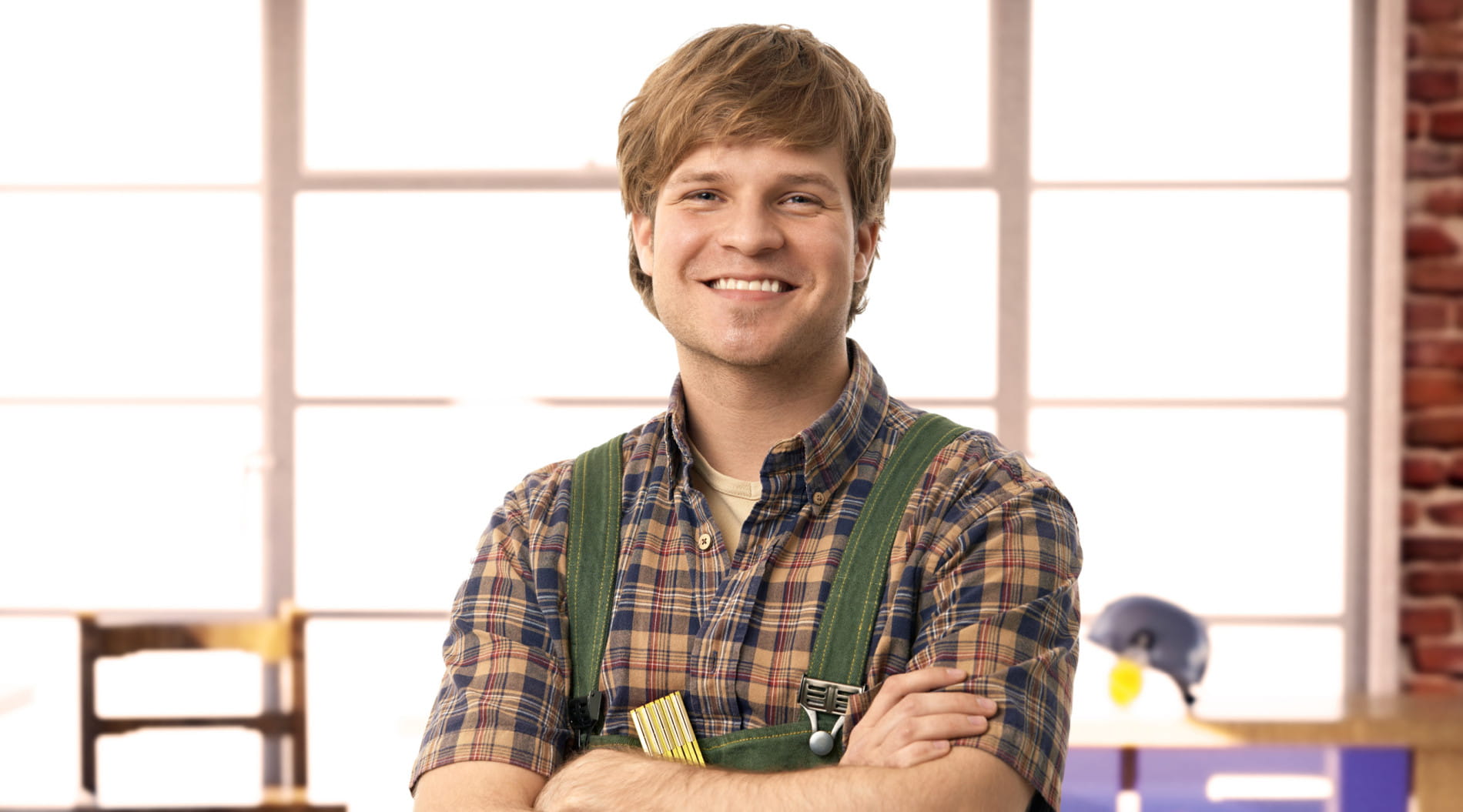 Person in plaid shirt with arms crossed by window