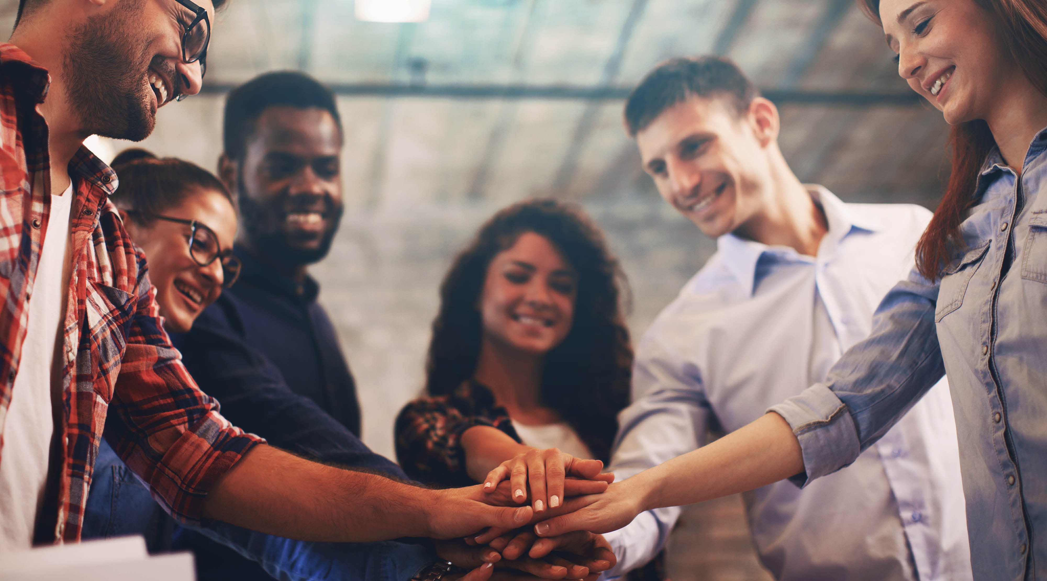 Group of people standing in a circle with hands stacked together