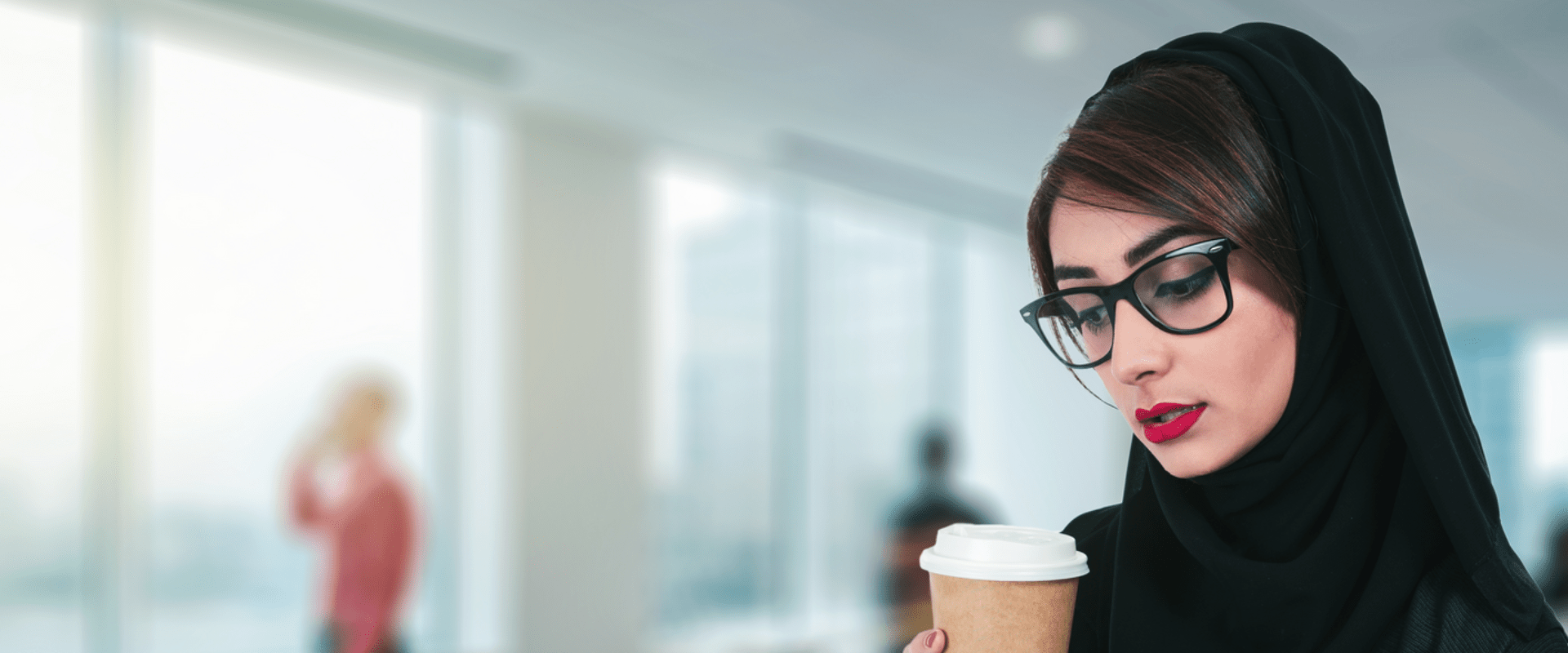 Arab attractive businesswoman drinking a coffee and using a digital tablet while standing in the office Arab attractive businesswoman drinking a coffee and using a digital tablet while standing in the office
