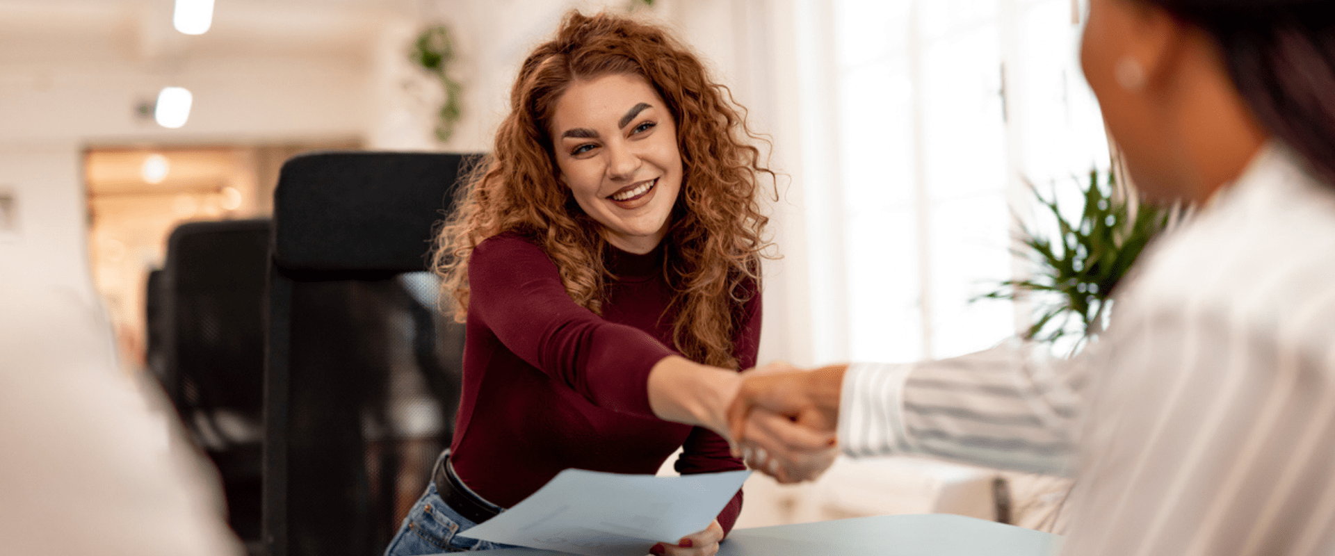 A job candidate shakes hands with their interviewer.