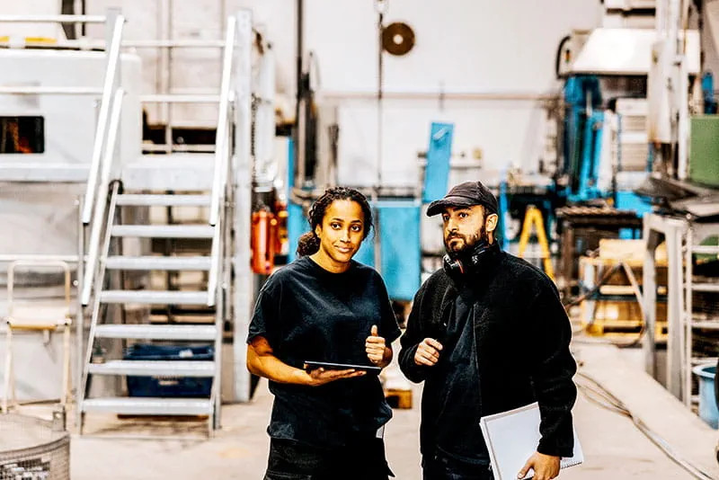 Two colleagues discussing work on a factory floor Two colleagues discussing work on a factory floor