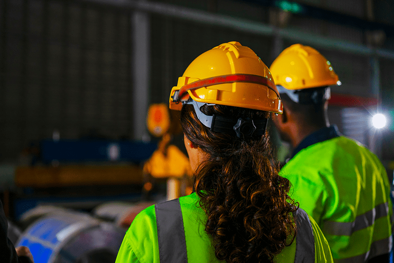 Manufacturing employees in safety gear working on a factory floor, highlighting employee engagement, workplace safety, and staff retention in industrial environments.