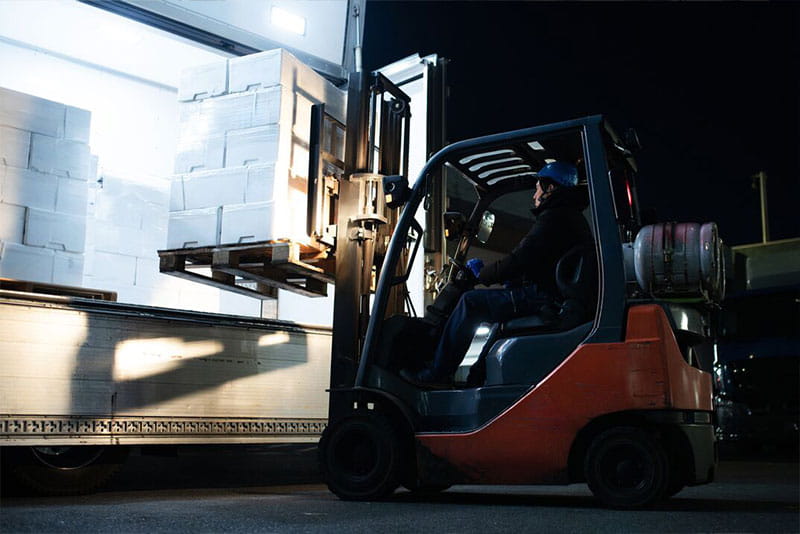 Forklift operator loading pallets onto a delivery truck at a busy warehouse during peak season. Forklift operator loading pallets onto a delivery truck at a busy warehouse during peak season.