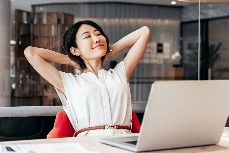Woman relaxing at her desk after working on a laptop Woman relaxing at her desk after working on a laptop