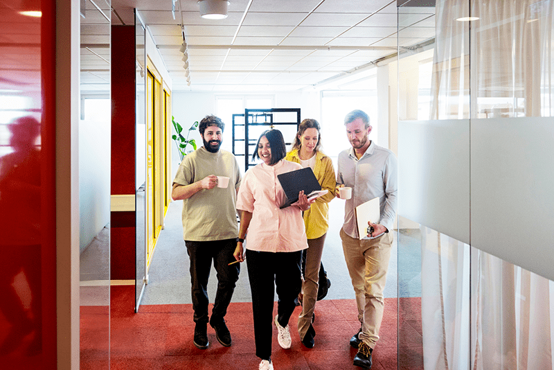 New employees and colleagues collaborating during workplace onboarding, walking through a modern office while discussing projects and team integration.