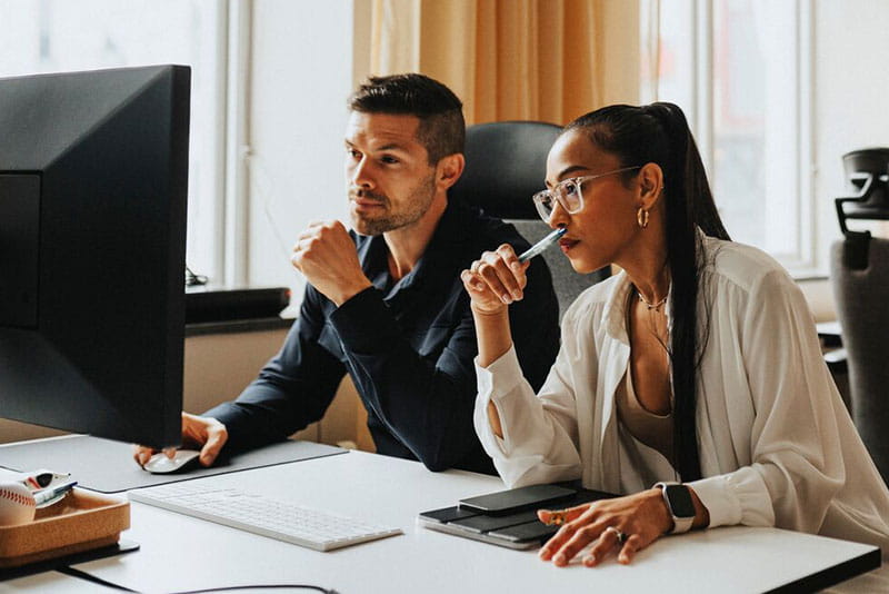 Two colleagues reviewing information on a computer in an office
