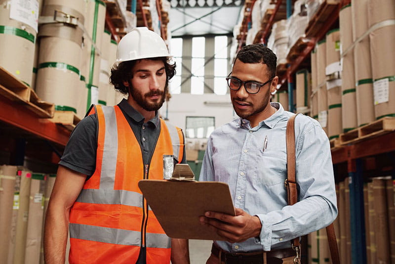 Warehouse worker and manager reviewing documents together Warehouse worker and manager reviewing documents together