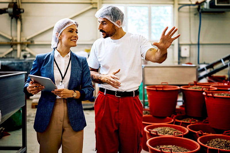 Manager and production worker discussing operations in a food processing facility Manager and production worker discussing operations in a food processing facility