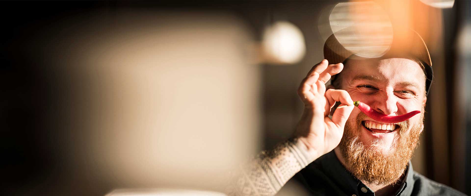 Lachende medewerker houdt speels een rood object voor één oog in creatieve werkruimte