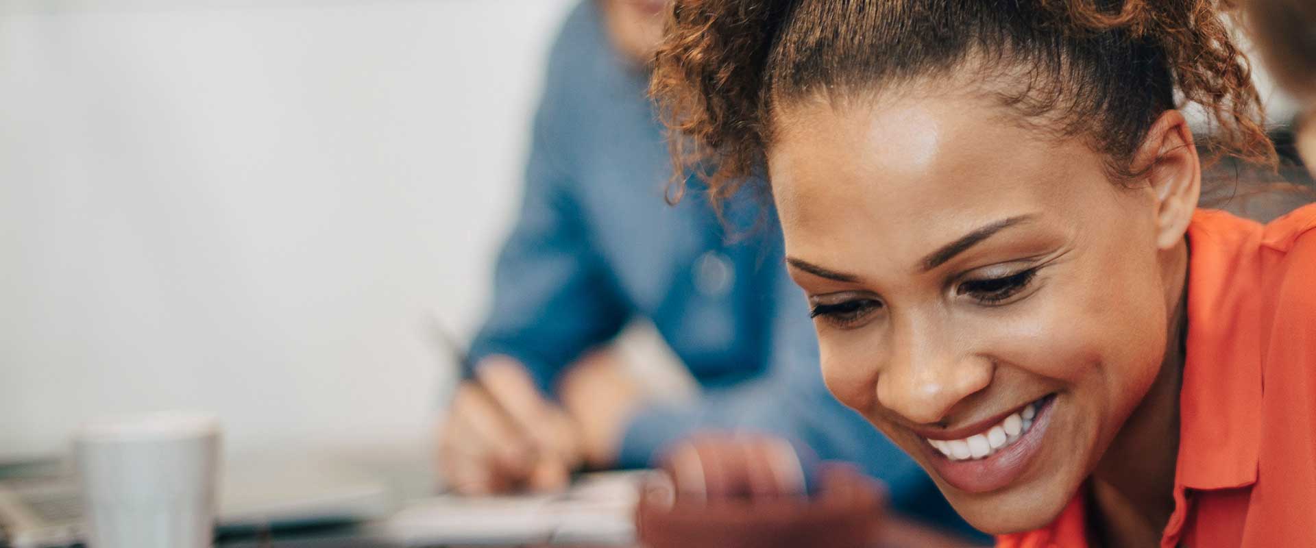 Professionele vrouw glimlacht terwijl ze aan een bureau werkt op kantoor