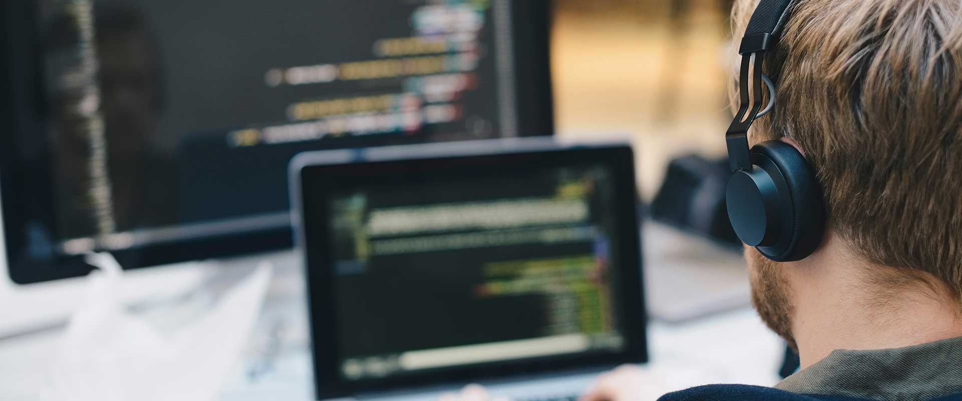 Développeur travaillant à un ordinateur avec du code visible à l'écran