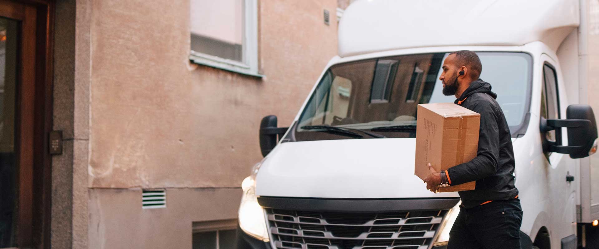 Chauffeur livreur transportant des boîtes depuis une fourgonnette lors d'une livraison locale